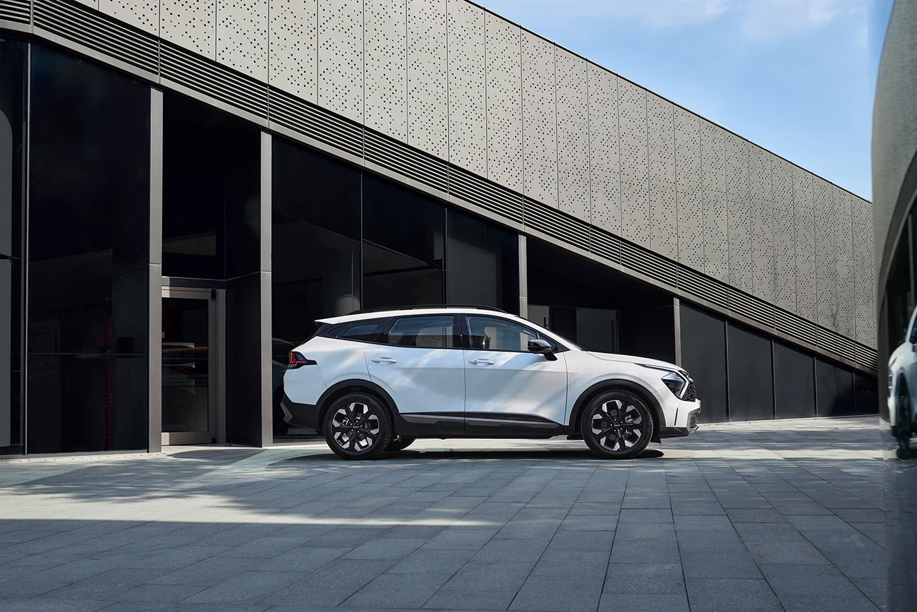 White China-market Kia Sportage side profile outside a modern building, 2025 manufacturer reference